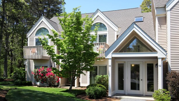 A two-story residential building with a front entrance, a small porch, and a balcony on the upper floor.