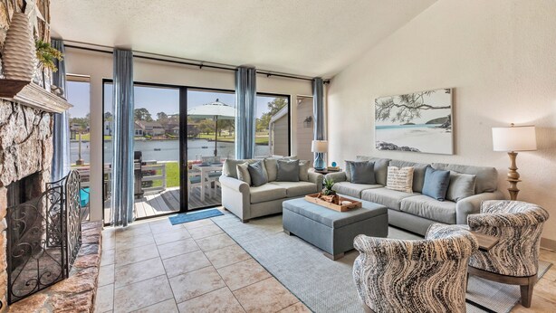 A spacious living room with a fireplace, two sofas, a coffee table, and a patterned armchair. - Lake Conroe WATERFRONT Updated 3BR Condo with Pools, Paddle Boards & Views (Montgomery)