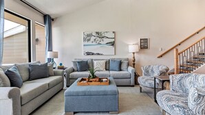 A living room with a grey sofa, a patterned armchair, and a wooden coffee table with a tray. - Lake Conroe WATERFRONT Updated 3BR Condo with Pools, Paddle Boards & Views (Montgomery)