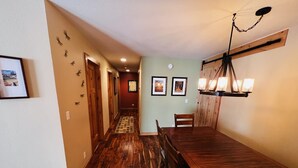 A wooden dining table with chairs, a chandelier, and framed pictures on the walls.