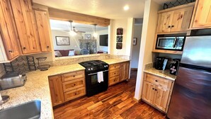 A kitchen with wooden cabinets, a stainless steel refrigerator, a microwave, and a stove.