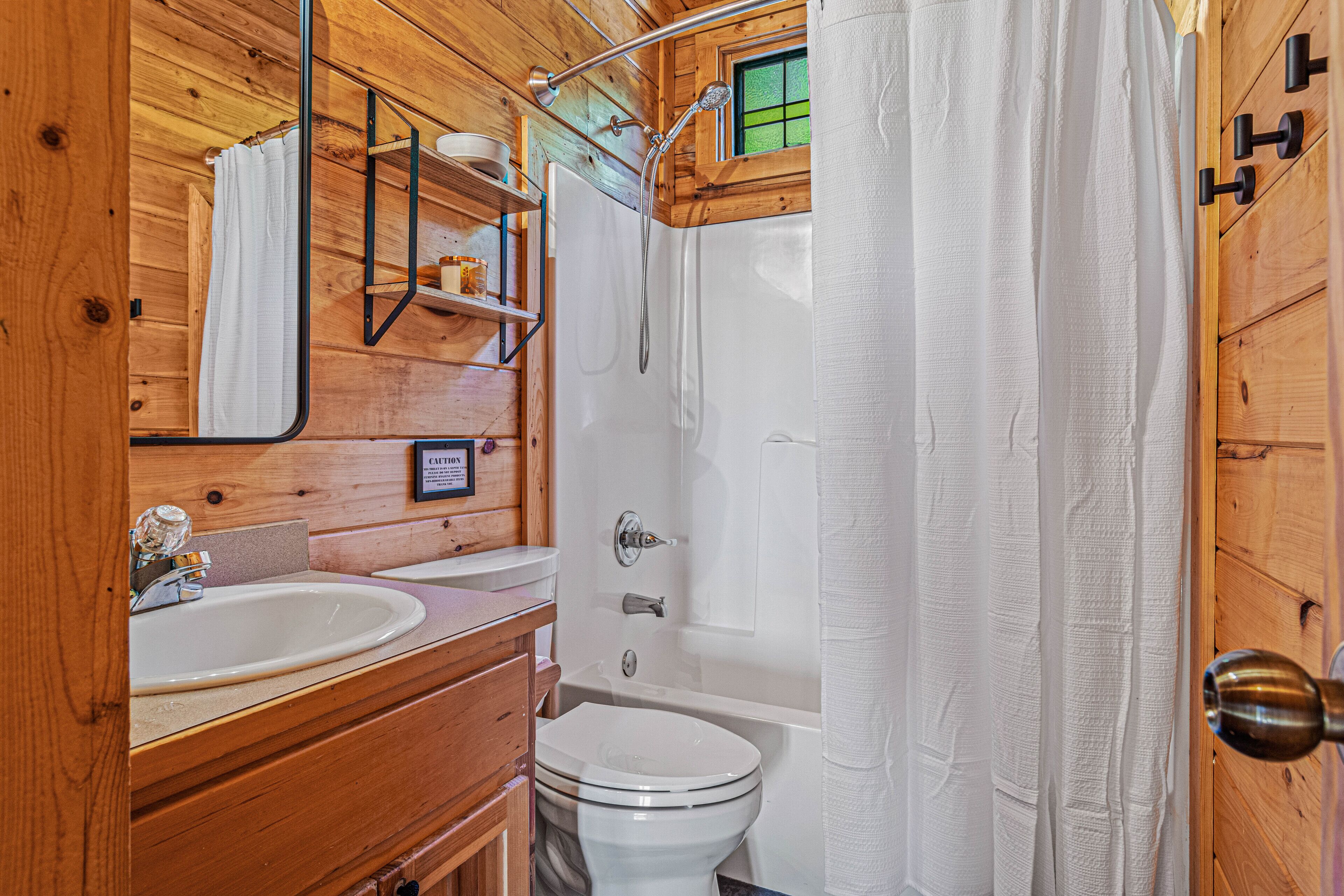 A wooden cabin bathroom with a shower, toilet, and two sinks.