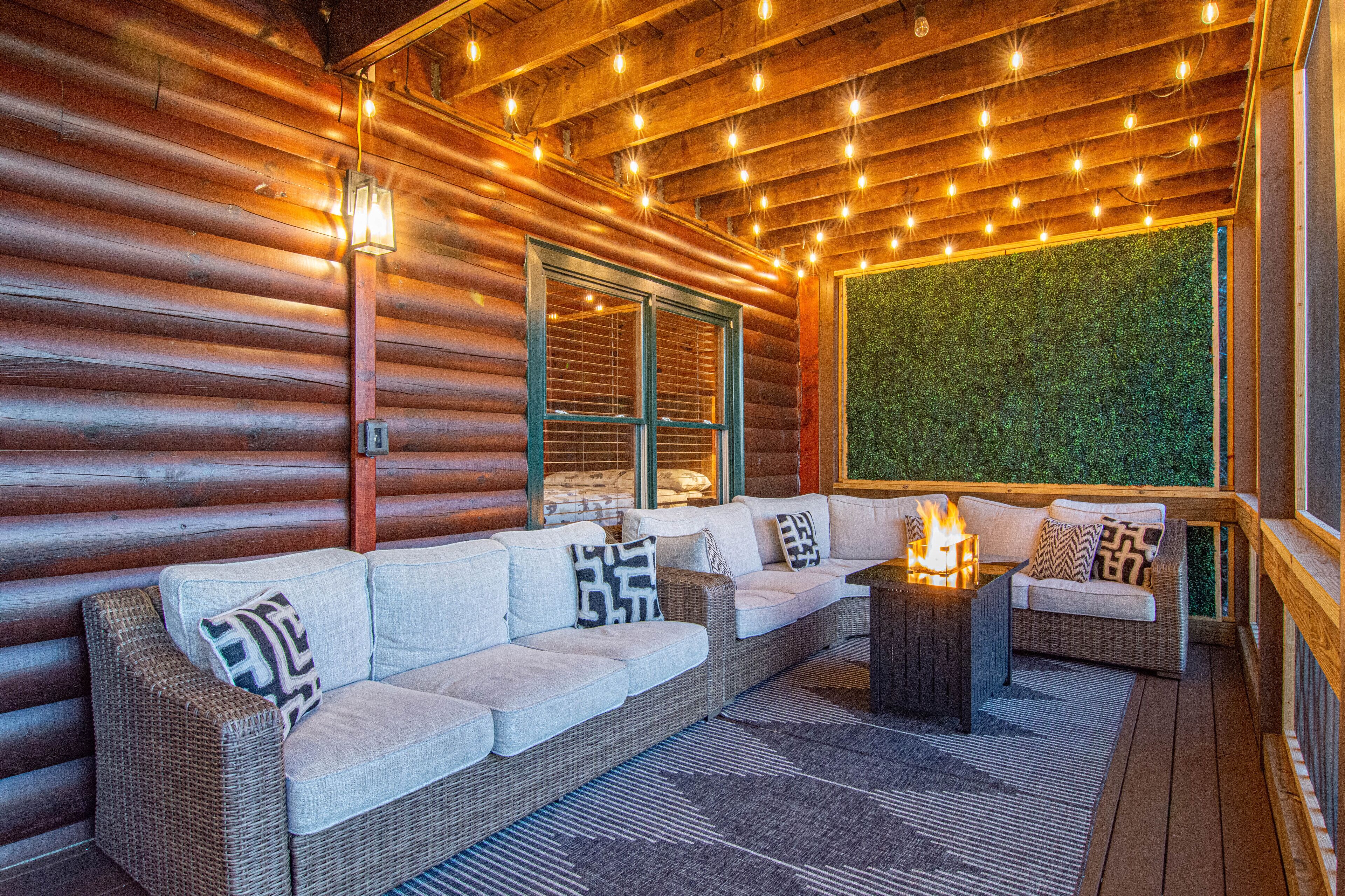 A log cabin interior with a large wicker sofa, a small table with a fire, and a green wall.