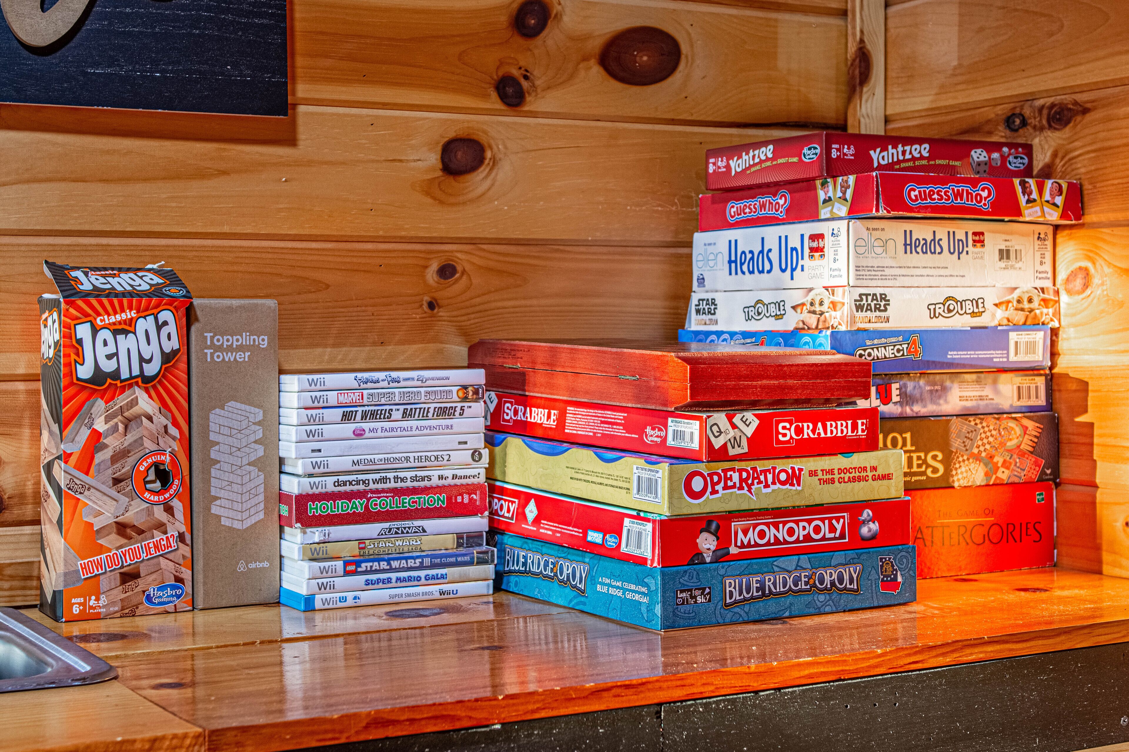 A collection of board games stacked on a wooden surface.
