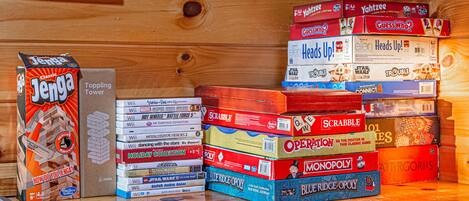 A collection of board games stacked on a wooden surface.