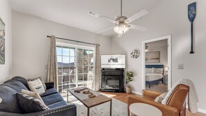 Un salon avec un canapé, une table basse et une cheminée. On y trouve également un ventilateur de plafond, un tableau et une enseigne sur laquelle on peut lire « Branson Lakes Lodge ».