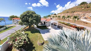 A coastal property with a large tree, a white building with a red roof, and a view of the sea. - Gated "Sea Breeze" House Overlooking the Caribbean (Patillas)