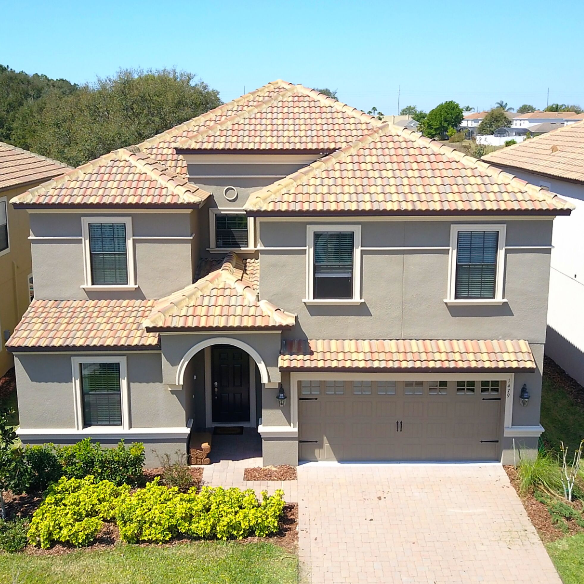A two-story house with a tiled roof, a garage, and a front entrance with a small porch.