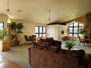 A spacious living area with a brown sofa, dining table, chairs, and large windows. - By Strip~Walk-In~Clean~2 Kings~Indoor Pool~HotTub (Branson)