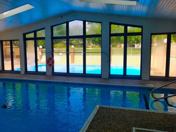 An indoor swimming pool with large windows, a lifebuoy, and a poolside area visible through the windows. - By Strip~Walk-In~Clean~2 Kings~Indoor Pool~HotTub (Branson)