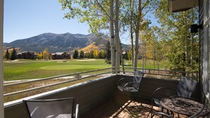 A balcony with a view of a golf course and mountains.