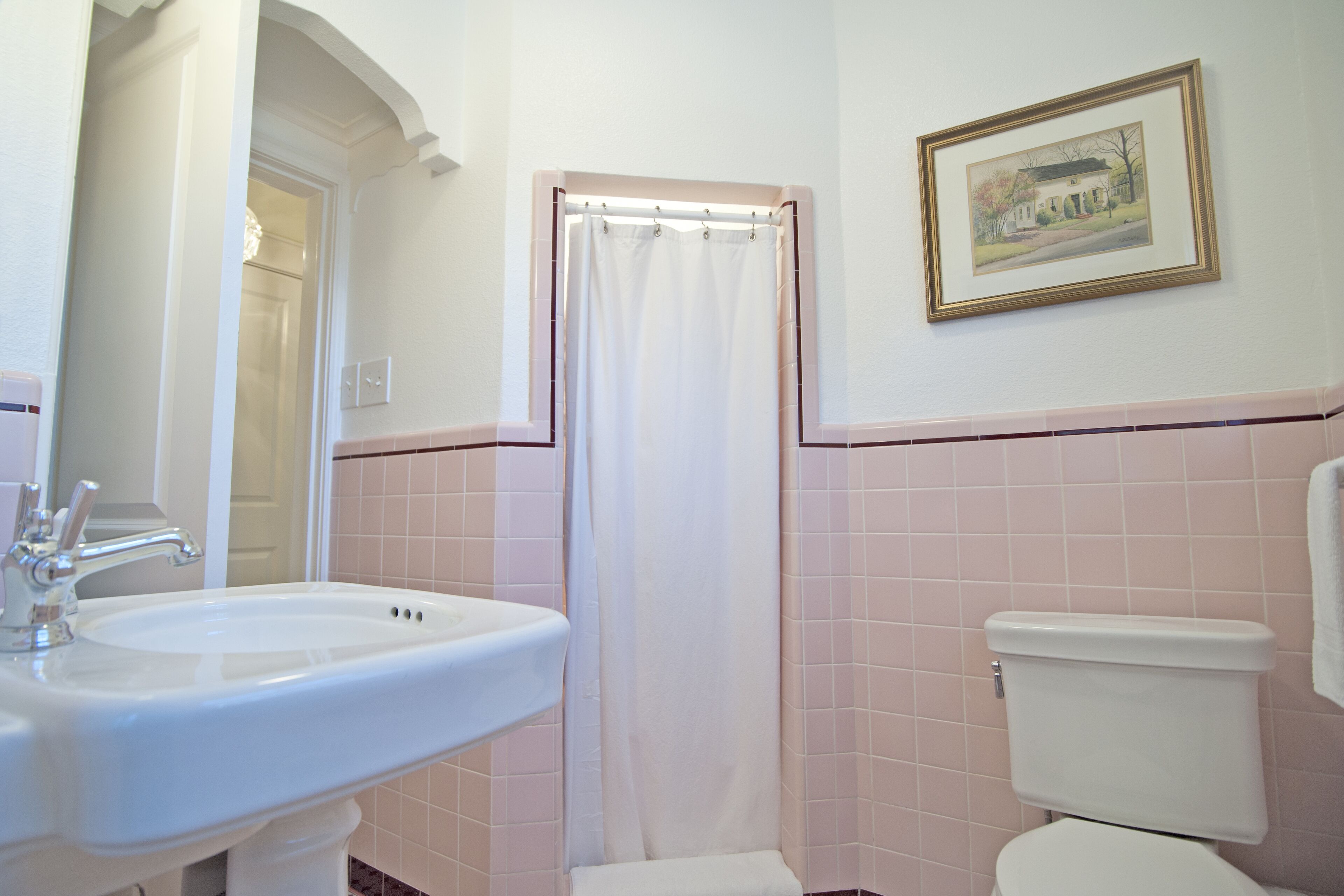 A bathroom with a white sink, a shower curtain, and a toilet.