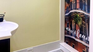 A bathroom with a shower curtain depicting a cityscape, a towel rack, and a small shelf with a basket.