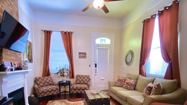 A living room with a fireplace, two sofas, a coffee table, and a ceiling fan.