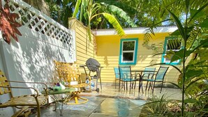 A patio area with a yellow wall, a white fence, and a table with chairs.
