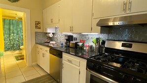 A modern kitchen with white cabinets, stainless steel appliances, and a tiled backsplash.