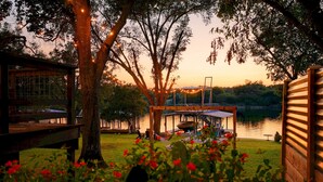 Un belvédère au bord du lac, offrant une vue sur l’eau, entouré d’arbres et doté d’une terrasse en bois.