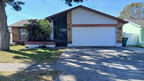 Une maison de plain-pied avec un garage, une façade en pierre et une pelouse bien entretenue.
