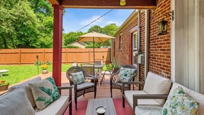 A covered patio with wicker furniture, a table, and a hanging lantern.
