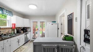 A modern kitchen with white cabinetry, a central island, and a chalkboard menu.