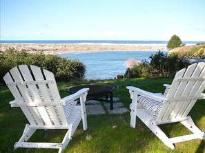 Deux fauteuils Adirondack sont placés face à un plan d’eau, offrant une vue sur la plage et l’océan.
