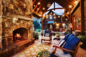 A rustic stone fireplace with a fire, wooden beams, a cozy seating area with patterned cushions, and a wooden exterior with a sign reading "Sic Em Reor". - Private, Lake-Front, Guest Suite on Lake Granbury, near downtown! (Granbury)