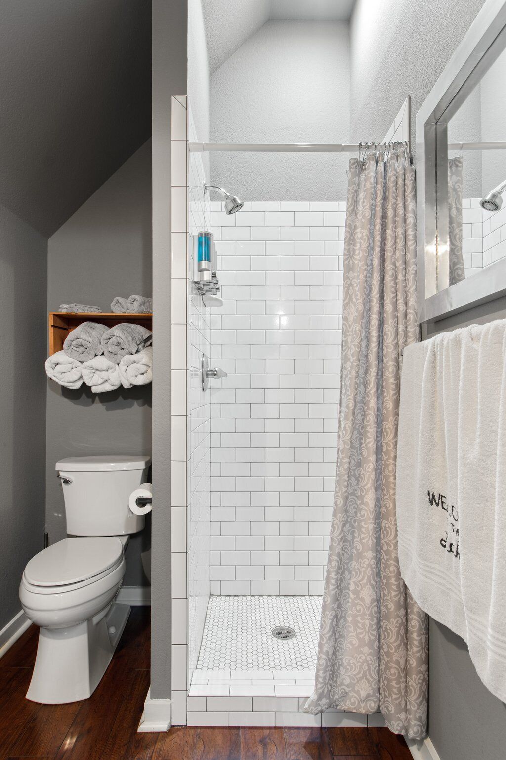 A bathroom with a white toilet, a shower with a glass door, and a towel rack with a towel.