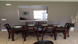 Un comedor con una mesa rectangular, seis sillas y un espejo grande sobre la mesa.
