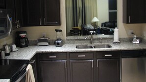 Una cocina con armarios oscuros, un fregadero, un tostador, una cafetera y una licuadora.