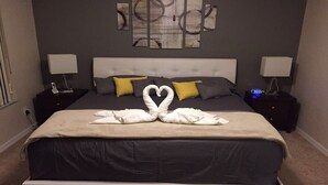 Habitación de hotel con una cama grande, dos mesitas de noche, un reloj de pared y arte abstracto en la pared.