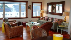 A living room with wicker furniture, a sofa with floral cushions, and a table with a lamp. - MENDO VILLAGE LUXURY OCEANFRONT PENTHOUSE, DOG FRIENDLY, VIEWS, WALK EVERYWHERE! (Mendocino)