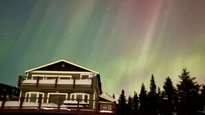 A two-story building with a balcony, surrounded by snow and trees. - The Best Alaskan Get Away Retreat For Your Family Or Group (Anchorage)