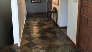 A hallway with a checkered floor, a wooden ceiling, a door, a wall-mounted air conditioning unit, and a framed map. - The Best Alaskan Get Away Retreat For Your Family Or Group (Anchorage)