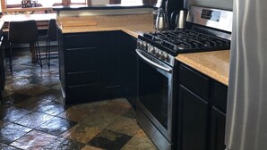 A kitchen with a central island, stainless steel appliances, and a stone tile floor. - The Best Alaskan Get Away Retreat For Your Family Or Group (Anchorage)