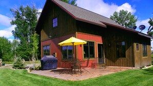 A wooden cabin with a patio, a barbecue grill, and a satellite dish.