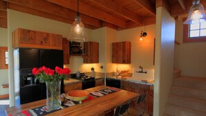 A rustic kitchen with wooden cabinets, a wooden dining table, and a vase with red roses.