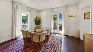 Un coin repas avec une table et des chaises en verre, un tapis aux couleurs vives et une vue sur l’extérieur.