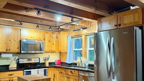 A kitchen with wooden cabinets, stainless steel appliances, and a wooden table.