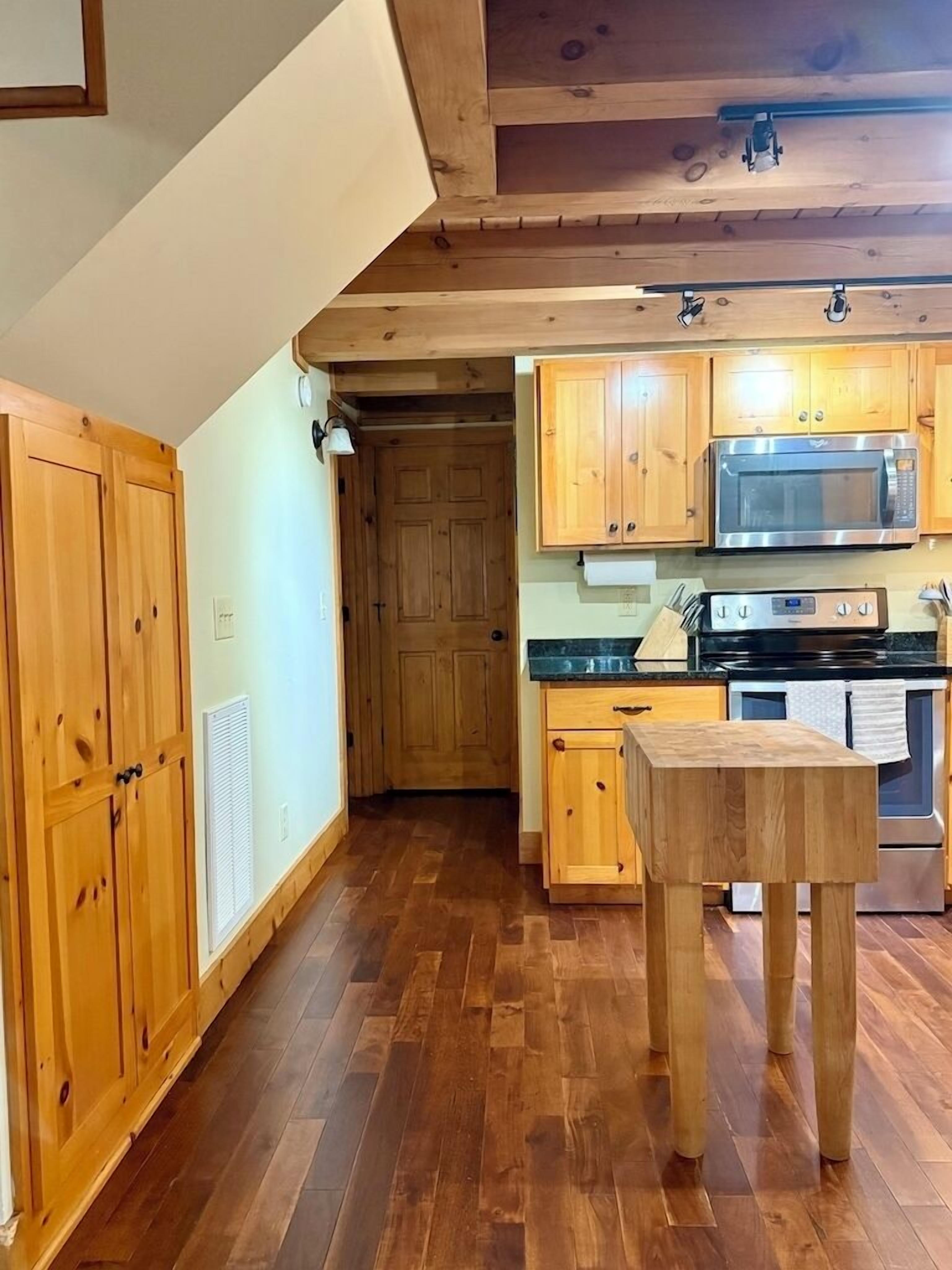 A kitchen with wooden cabinets, a microwave, an oven, and a wooden table.
