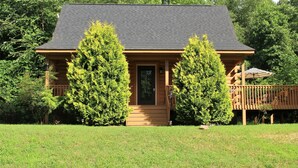 A cabin with a dark roof, wooden siding, and a front porch.
