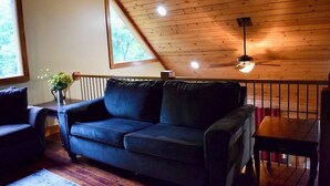 A cozy room with a dark blue sofa, a small table, and a ceiling fan.