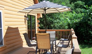A wooden deck with outdoor furniture, including chairs and a table, and a striped umbrella. - Pleasant Country Cabin - Convenient to TIEC (Rutherfordton)