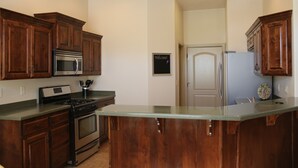 A kitchen with wooden cabinets, stainless steel appliances, and a glass island counter.