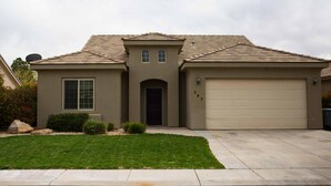 A single-story house with a beige facade, a dark brown front door, and a garage door.