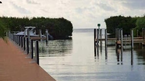 A wooden dock extending into calm water with a row of metal posts and a green sign. - Bright & Sunny Suite w/ Magnificent Ocean Views (Tavernier)