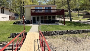 A two-story house with a balcony, a covered patio, and a wooden deck leading to the entrance.