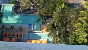Luchtbeeld van een resort met een zwembad, palmbomen en een strand.