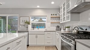 A modern kitchen with white cabinetry, a built-in oven, and a gas stove.