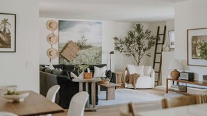 A living room with a sofa, coffee table, and a painting of a landscape.