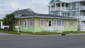 A two-story house with a green facade, white trim, and pink shutters.